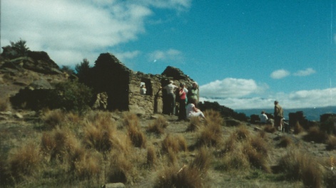 A group of people standing among stone ruins on a hilltop under a blue sky.