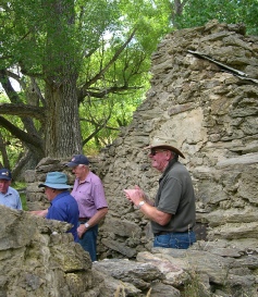 A group of people in sun hats examining a tumbled stone ruin among trees