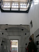 Interior of the Arrowtown Gaol showing a barred cell door below an upper landing and balcony rail