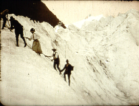 Vintage black-and-white film still of a roped party of climbers and a guide crossing a steep snow and ice slope in the mountains