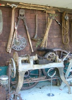 A cluttered wall of old tools and machinery, including shears and pulleys, displayed in a workshop-like collection.