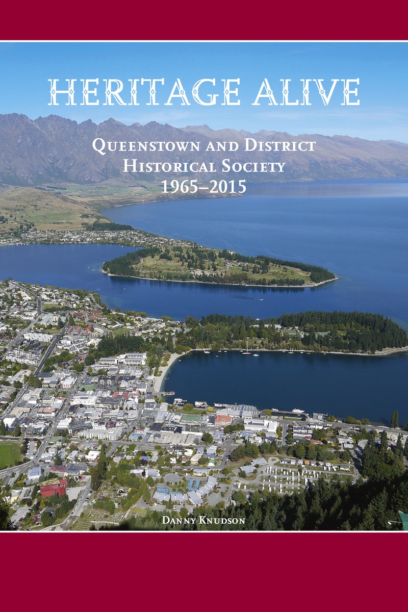 Book cover with an aerial photograph of Queenstown, its bay and the peninsula gardens under the mountains, titled Heritage Alive, Queenstown and District Historical Society 1965 to 2015, by Danny Knudson