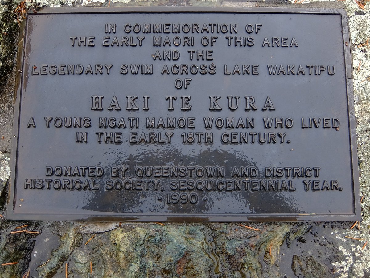 Cast metal plaque bolted to a rock, its raised capitals commemorating the early Maori of the area and the legendary swim across Lake Wakatipu of Haki Te Kura, 'a young Ngati Mamoe woman who lived in the early 18th century', with a donation line below from the Queenstown and District Historical Society, dated 1990