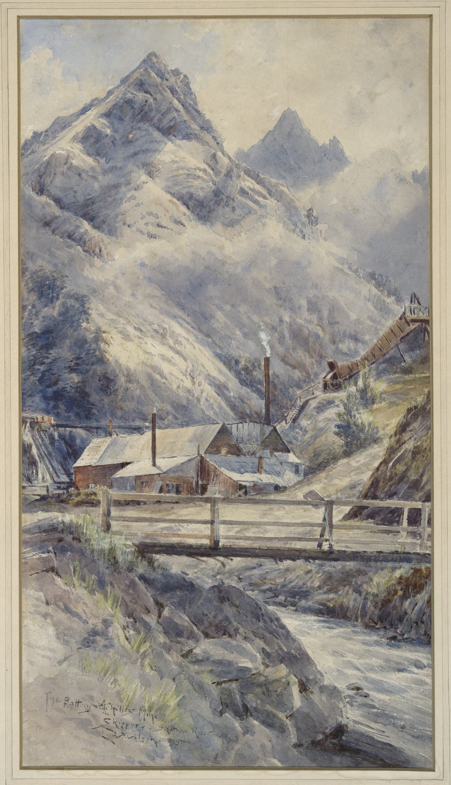 Watercolour looking up a narrow valley to a cluster of mine buildings with a smoking chimney, a timber chute descending the hillside above them, snow-streaked peaks behind and a plank bridge over the creek in the foreground